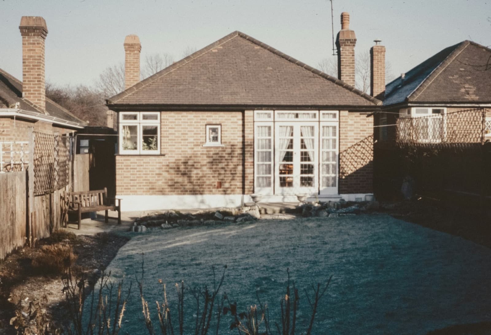 Older brick bungalow backyard with a simple lawn and fences — everyday homes in ordinary neighborhoods